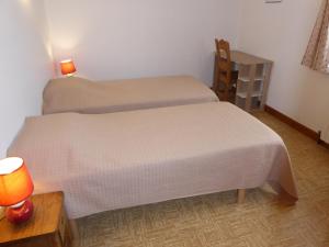 two beds in a room with a lamp and a table at Appartement REINE DES PRES in Megève