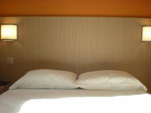 ラベージュにあるPremiere Classe Toulouse Sud Labegeの白い枕2つ付きのベッド1台