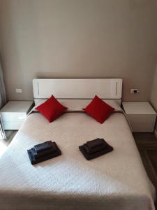 un letto bianco con due cuscini rossi sopra di Appartamento Piccola Perla a Cologno Monzese