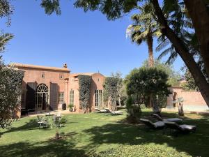 een binnenplaats van een huis met palmbomen en stoelen bij Villa #1 ‘Rosalie’ in Marrakesh