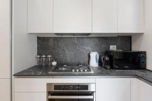 a kitchen with a stove top oven next to a microwave at Naviglio Dream - 2 bedrooms 2 bathrooms in Milan