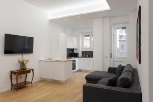 a living room with a black couch and a kitchen at Naviglio Dream - 2 bedrooms 2 bathrooms in Milan