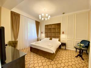 ブカレストにあるVenetian Bucharestのベッドとシャンデリアが備わるホテルルームです。