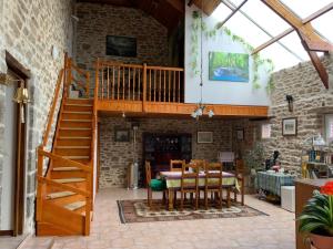 a wooden staircase in a house with a table and chairs at Le Bois Chef D'Ane in Collinée