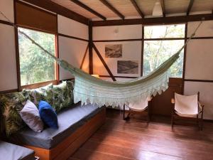 a hammock in a room with a couch and windows at Caraguatás in Cunha