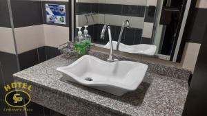 a bathroom counter with a sink and two mirrors at Hotel Centenario Plaza in Belén