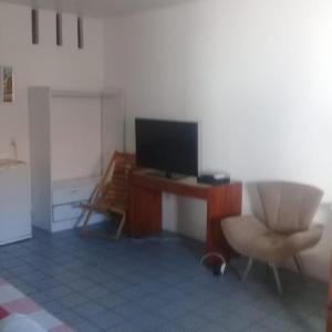 a living room with a television and a desk with a chair at Pousada Só Alegria in Fortaleza