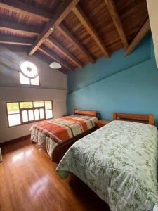 Cette chambre comprend 2 lits dans une chambre dotée de murs bleus et d'une fenêtre. dans l'établissement Lodge Acopampa Inn, à Carhuaz