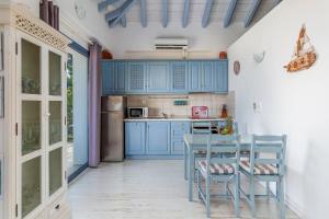 a kitchen with blue cabinets and a table and chairs at Villa Galazopetra in Skopelos Town