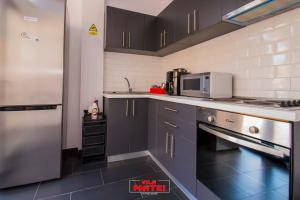 a kitchen with black cabinets and a stainless steel refrigerator at Vila Matei - Eforie Nord in Eforie Nord