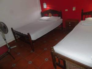 a room with two beds and a red wall at Hostal Vacaciones Nicas in León