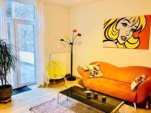 ein Wohnzimmer mit einem orangenen Sofa und einem Gemälde in der Unterkunft Lyves Two in Lüttich