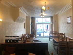 a restaurant with tables and chairs and a large window at Leecliff Guest House in Blackpool