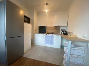 uma cozinha com armários brancos e um frigorífico em Appartement, parking gratuit, sortie, autoroute, la méridienne em Clermont-Ferrand
