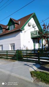 a white house with a green fence in front of it at Bamboo Apartman in Siófok