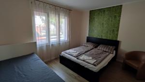 ein Schlafzimmer mit einem Bett, einem Fenster und einem Stuhl in der Unterkunft Bamboo Apartman in Siófok