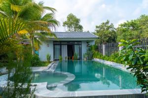 a swimming pool in a backyard with a house at Khu Nghỉ Dưỡng Green Bungalow Phu Quoc in Phu Quoc
