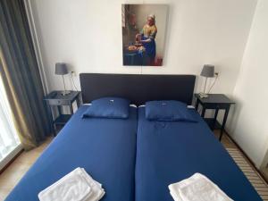 ein blaues Bett mit blauen Kissen im Schlafzimmer in der Unterkunft Hotel 't Sonnehuys in Scheveningen