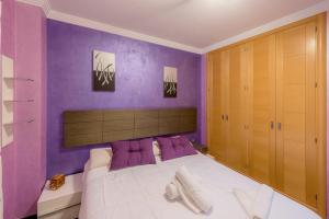 una camera da letto con pareti viola e un letto con cuscini viola di Apartamento Céntrico Sibarys-3 dormitorios a Nerja