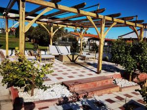 a patio with a wooden pergola and benches at Rural villa Private pool, BBQ, court ,20' airport in Nea Kallikrateia
