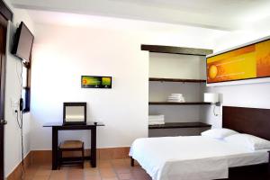 Schlafzimmer mit einem Bett und einem Schreibtisch mit einem Laptop in der Unterkunft Chrisban Hotel Boutique in Buga