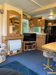a room with a kitchen with a table and a tv at Forest View - Adults Only - Maximum 2 Guests in Drumnadrochit