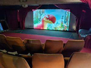 a stage with chairs and a screen with a dinosaur on it at Gite Ty Nid Le 1900 in Val Couesnon