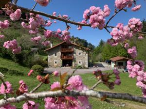 ein Gebäude mit rosa Blumen vor einem Baum in der Unterkunft Agroturismo Urresti in Gautegiz Arteaga