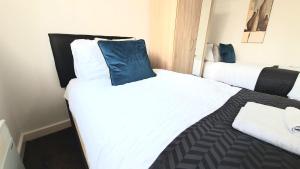 Salford Ark Comfort Stays near Salford Royal and Trafford Centre في مانشستر: غرفة نوم بسريرين مع وسائد بيضاء وزرقاء