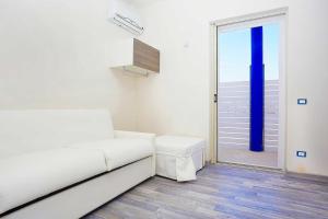 a white room with a white couch and a sliding glass door at Stabilimento Lido Burrone in Favignana