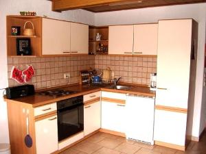 uma cozinha com armários brancos e um forno com placa de fogão em Fewo Mühlehof em Königshain
