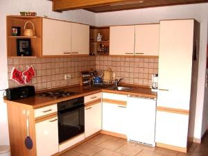 a kitchen with white cabinets and a stove top oven at Fewo Mühlehof in Königshain