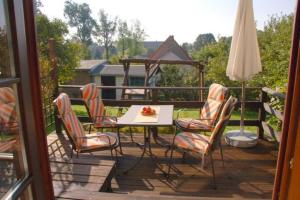 eine Terrasse mit einem Tisch, Stühlen und einem Sonnenschirm in der Unterkunft Fewo Mühlehof in Königshain