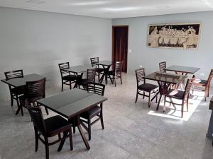 a dining room with tables and chairs and a painting on the wall at Botelho Hotel in Arapongas