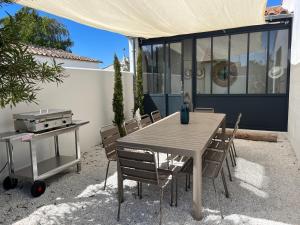 een tafel en stoelen en een grill op een patio bij Villa Miha (New house Saint Martin de Ré) in Saint-Martin-de-Ré