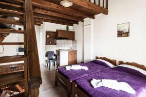 a bedroom with a purple bed and a kitchen at Despina Studios 4 beds with loft and kitchenette # 8 in Raches