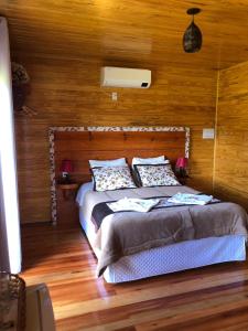 1 dormitorio con 1 cama grande y paredes de madera en Hospedagem Família Cruz, en Urubici