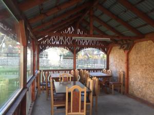 a restaurant with wooden tables and chairs and windows at Pensiunea Emage Moieciu in Moieciu de Sus