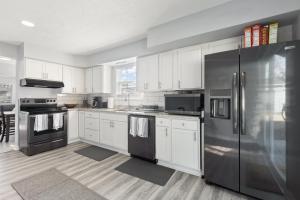 a kitchen with white cabinets and a stainless steel refrigerator at Entire Home Near MSU and Local Hospitals with Fast Wi-Fi & Dedicated Office in Lansing