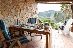 Un patio con paredes de piedra con una mesa y sillas de madera. en Quinta Da vida Serena, en Gaio
