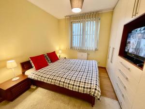 1 dormitorio con 1 cama con almohadas rojas y TV en New HALA WiFi 70’TV Netflix HBO Max AppletTV+, en Varsovia