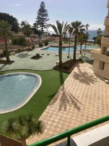 Una vista de un resort con piscina y palmeras. en Apartamentos Costamar, en Arona