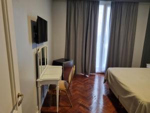 um quarto de hotel com uma cama, uma secretária e uma televisão em HOTEL REGIS em Buenos Aires