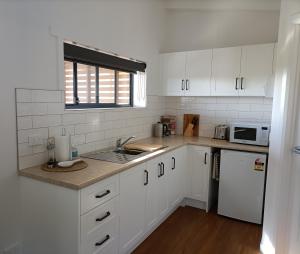 a kitchen with white cabinets and a sink and a microwave at Spiritwood, BnB for 2 in a quiet rural setting in Lower Barrington