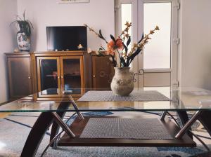 une table en verre avec un vase et des fleurs sur lui dans l'établissement Apartment Katica Mostar, à Mostar