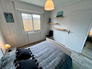 ein Schlafzimmer mit einem Bett und einem Fenster in der Unterkunft Villa Petit-Père - à 400m de la plage in Taussat-les-Bains