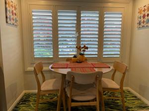 uma sala de jantar com mesa, cadeiras e janelas em Highlands Riad em Moss Vale