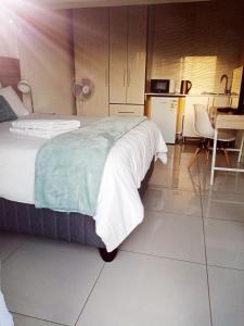 a bedroom with a large bed and a kitchen at Langa's Gabedi Goshen in Pretoria