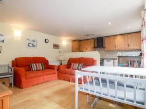 a living room with two red couches and a kitchen at Honeysuckle in Gorran Haven