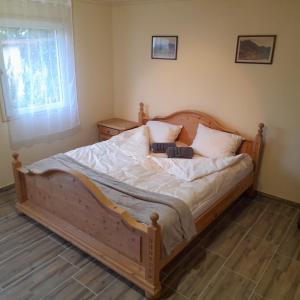 1 dormitorio con 1 cama de madera y 2 almohadas en Őrségi Kistücsök Vendégház en Hegyhátszentmárton